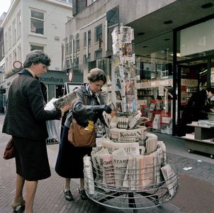846368 Afbeelding van een standaard met kranten en prentbriefkaarten bij boekhandel Bruna (Choorstraat 13) te Utrecht.